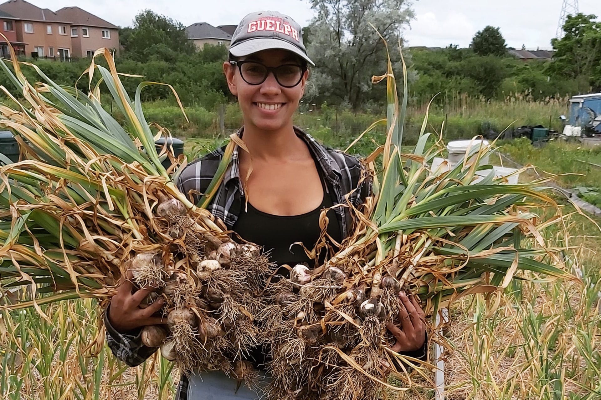 Rav Singh standing in the middle of a field holding her crops.