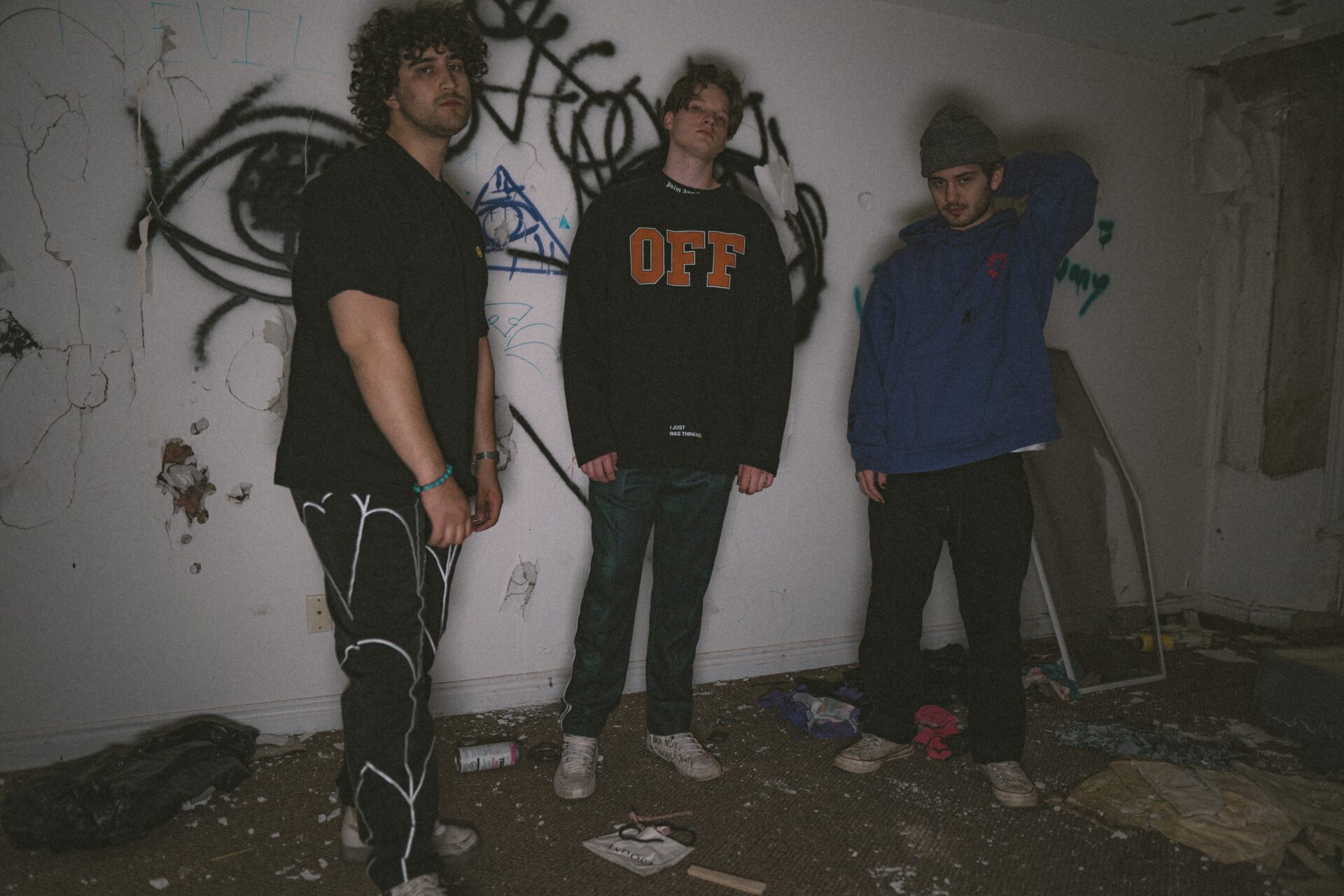 Members of Bloom Media standing in front of a graffitied white wall